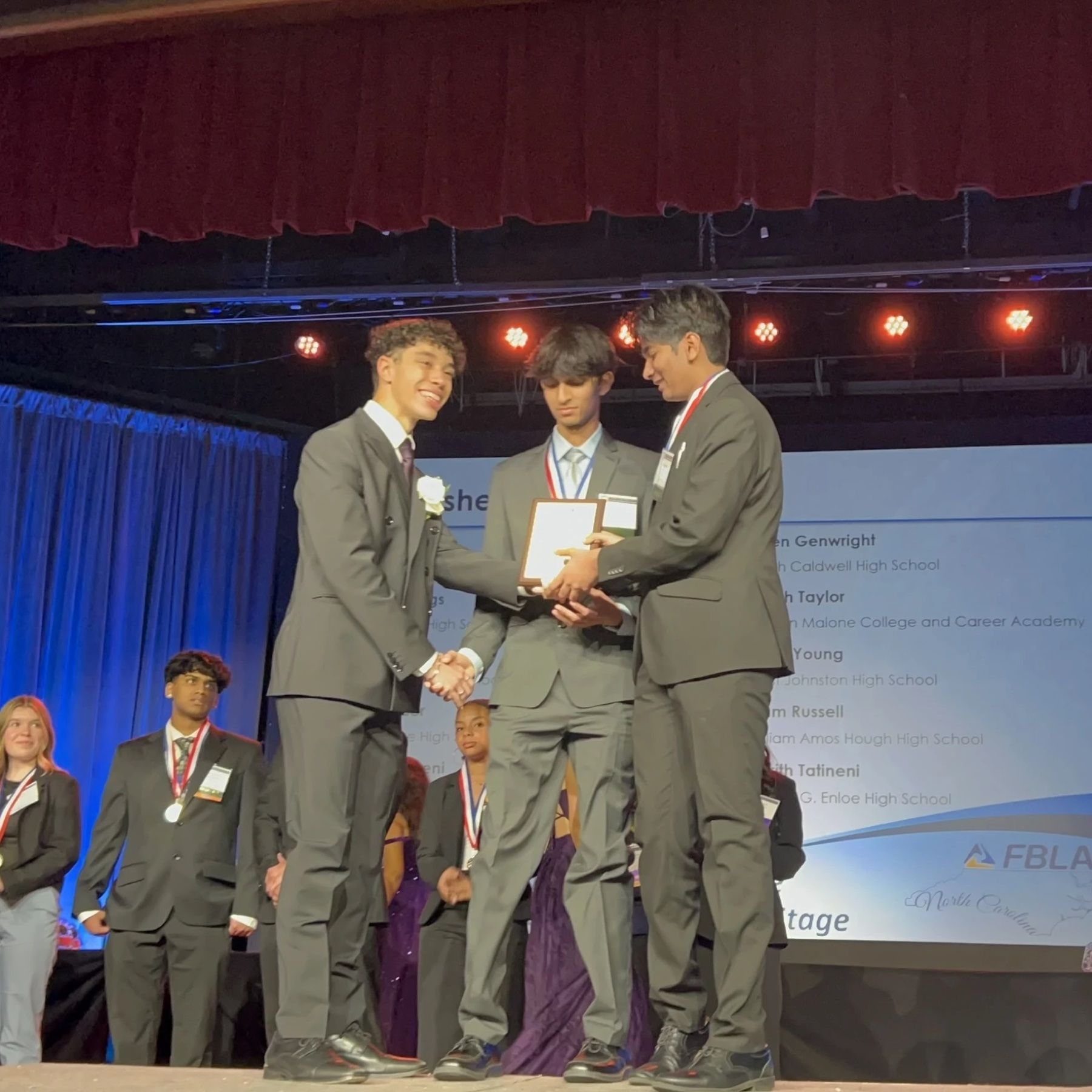 Jason standing between two students on stage at an FBLA North Carolina awards ceremony.