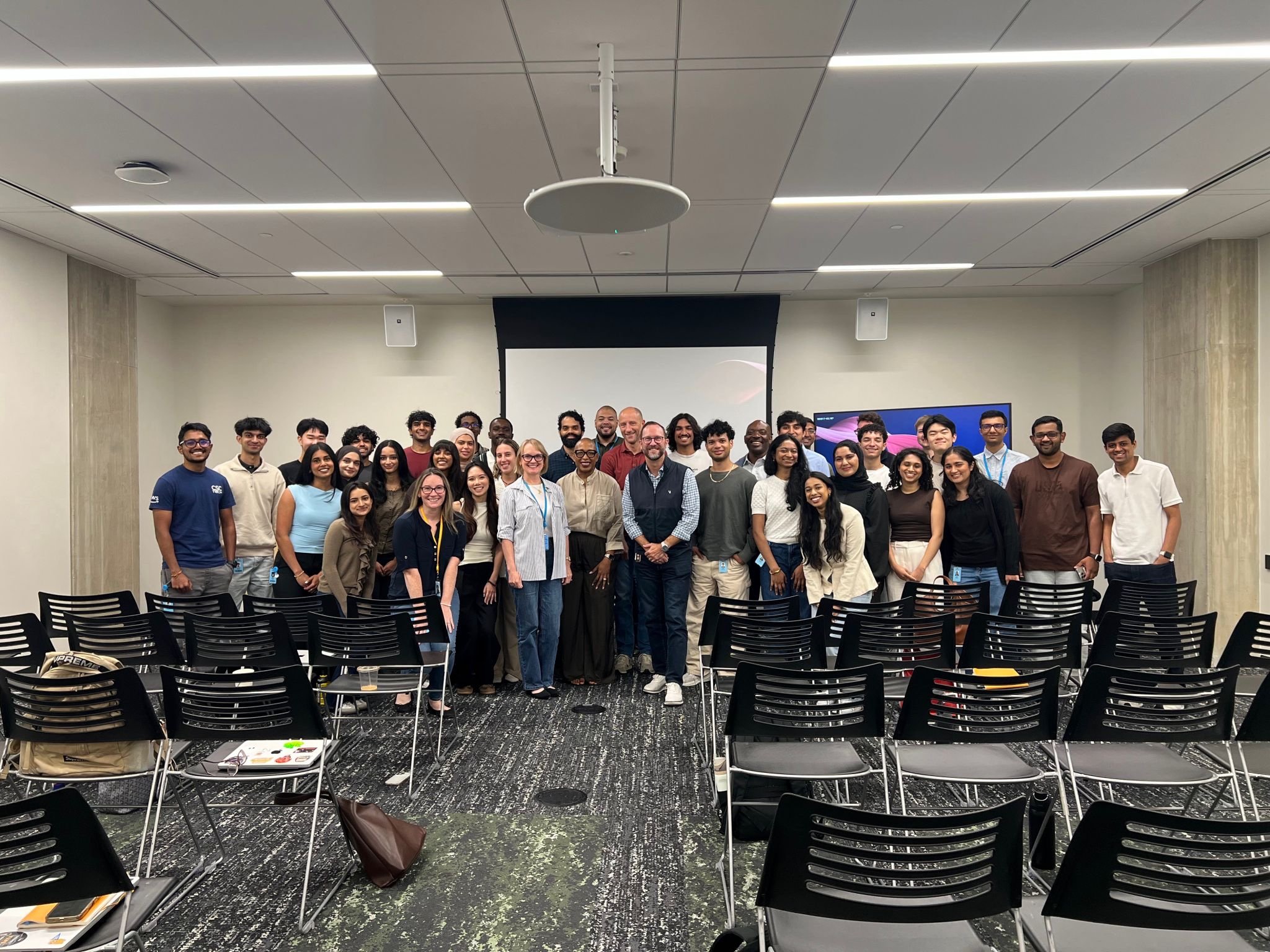 A large group of AWS interns and staff in a presentation room.