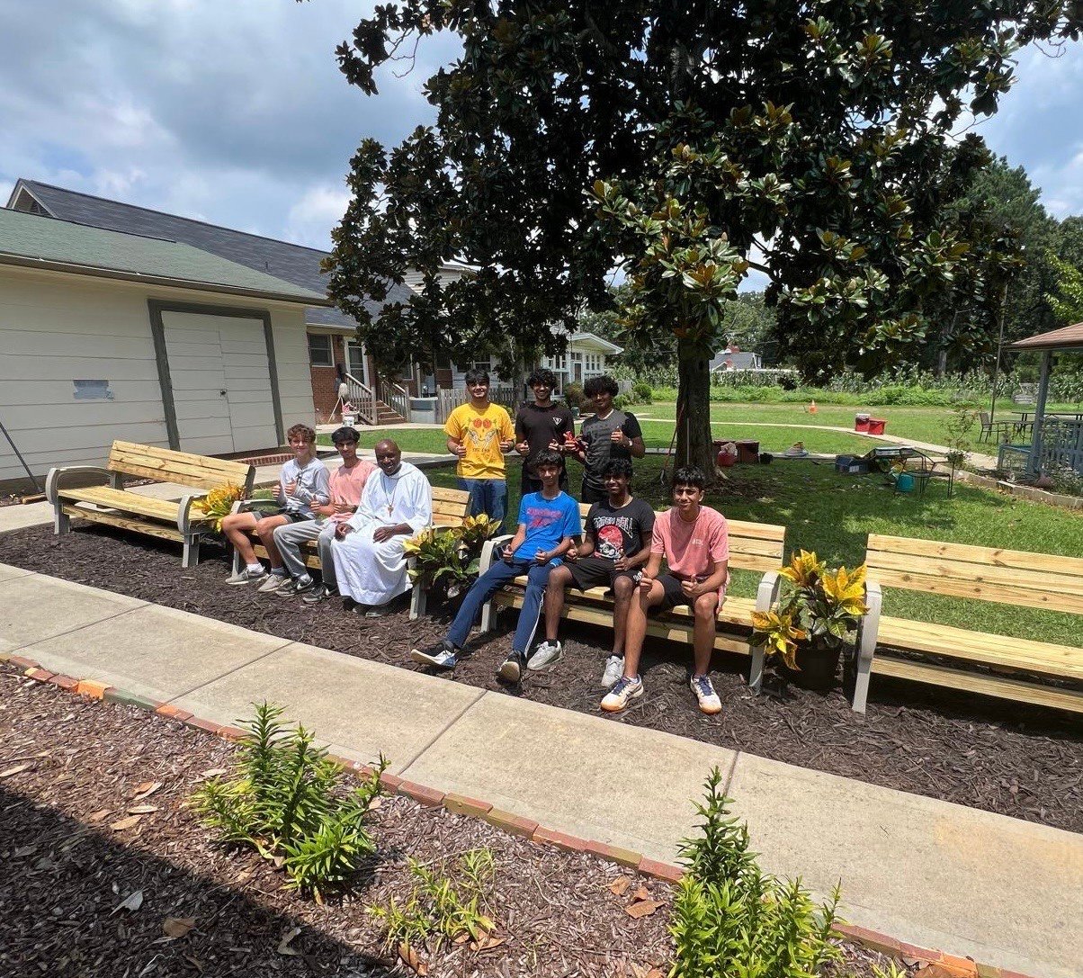 Jason's Eagle project crew seated on the new wooden benches in a freshly mulched garden bed.